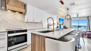 Una cucina moderna con mobili bianchi, un'isola centrale e un forno integrato.