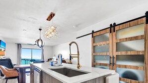 Una cucina moderna con isola centrale, un lampadario e vista all'esterno.