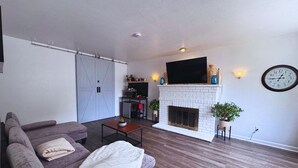 Un salon avec une cheminée, un canapé, une table basse et un téléviseur.