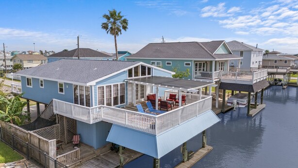 A waterfront house with a covered patio, a small deck, and a boat dock. - The Bent Rod-Charming Canal home! (Jamaica Beach)