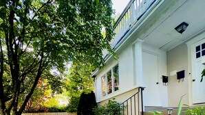 A two-story house with a front porch, a staircase leading to the entrance, and a well-maintained lawn.
