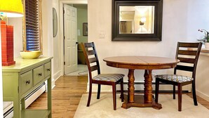 A dining area with a wooden table, two chairs, a ceiling fan, and a mirror on the wall.