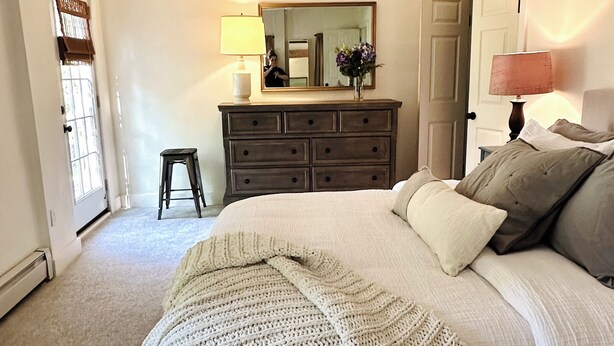 A bedroom with a bed, a dresser, a mirror, and a lamp.