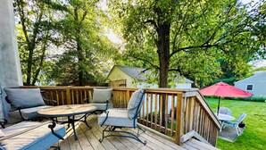 A wooden deck with outdoor furniture, including a round table and chairs, and a red umbrella.