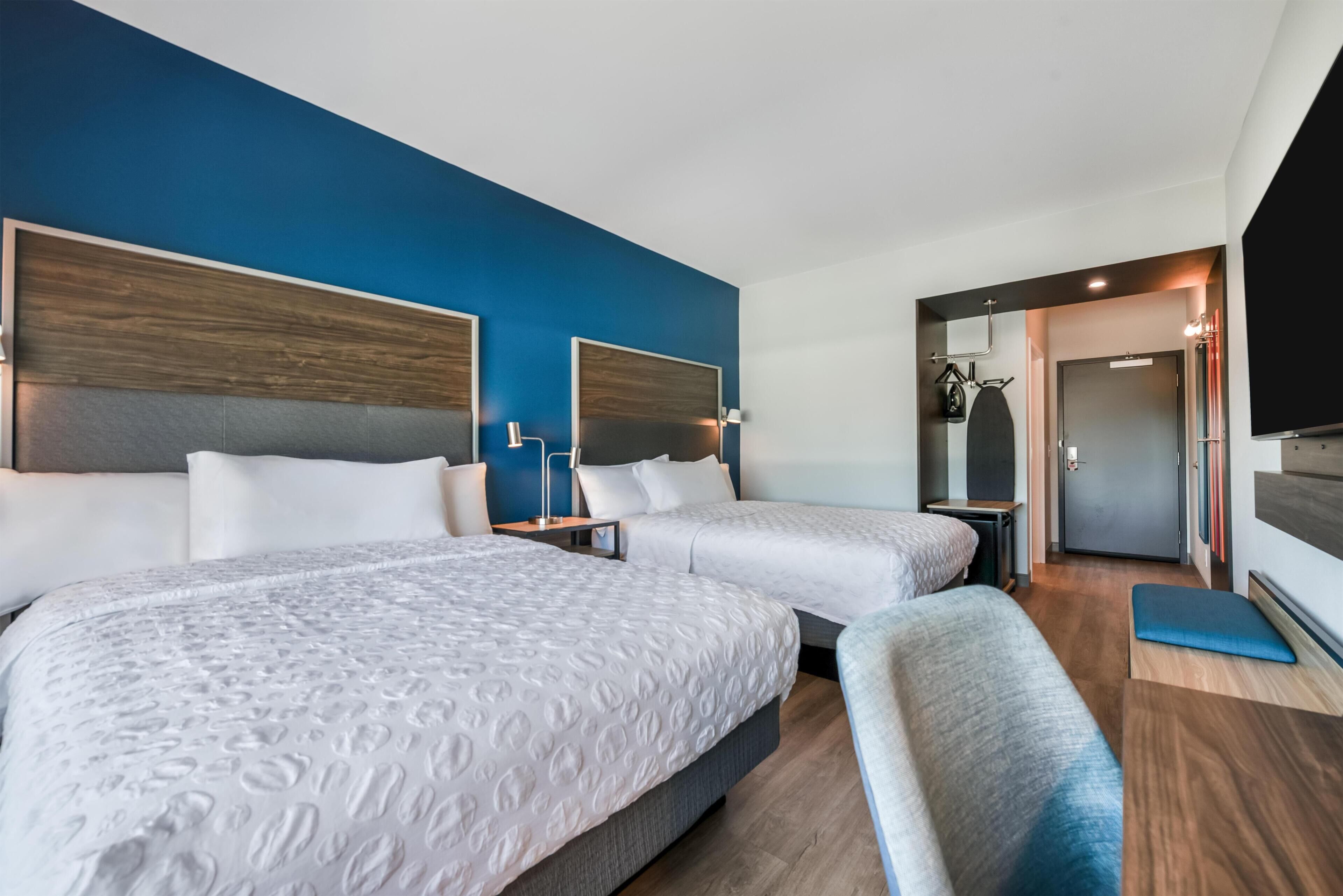 Une chambre d’hôtel avec deux lits, un coin salon, une télévision et une porte donnant accès à la salle de bain.