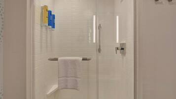 Une salle de bain moderne avec une douche à parois de verre, des murs recouverts de carreaux blancs et une serviette blanche posée sur un porte-serviettes.