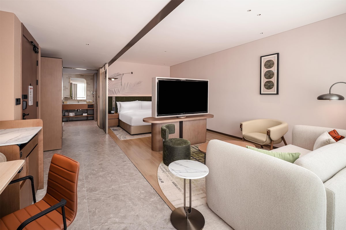 Een moderne hotelkamer met een flatscreen televisie, een bank, een zithoek en een afzonderlijke slaapkamer.