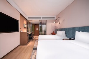 Una habitación de hotel moderna con una cama grande, un escritorio y un televisor de pantalla plana.