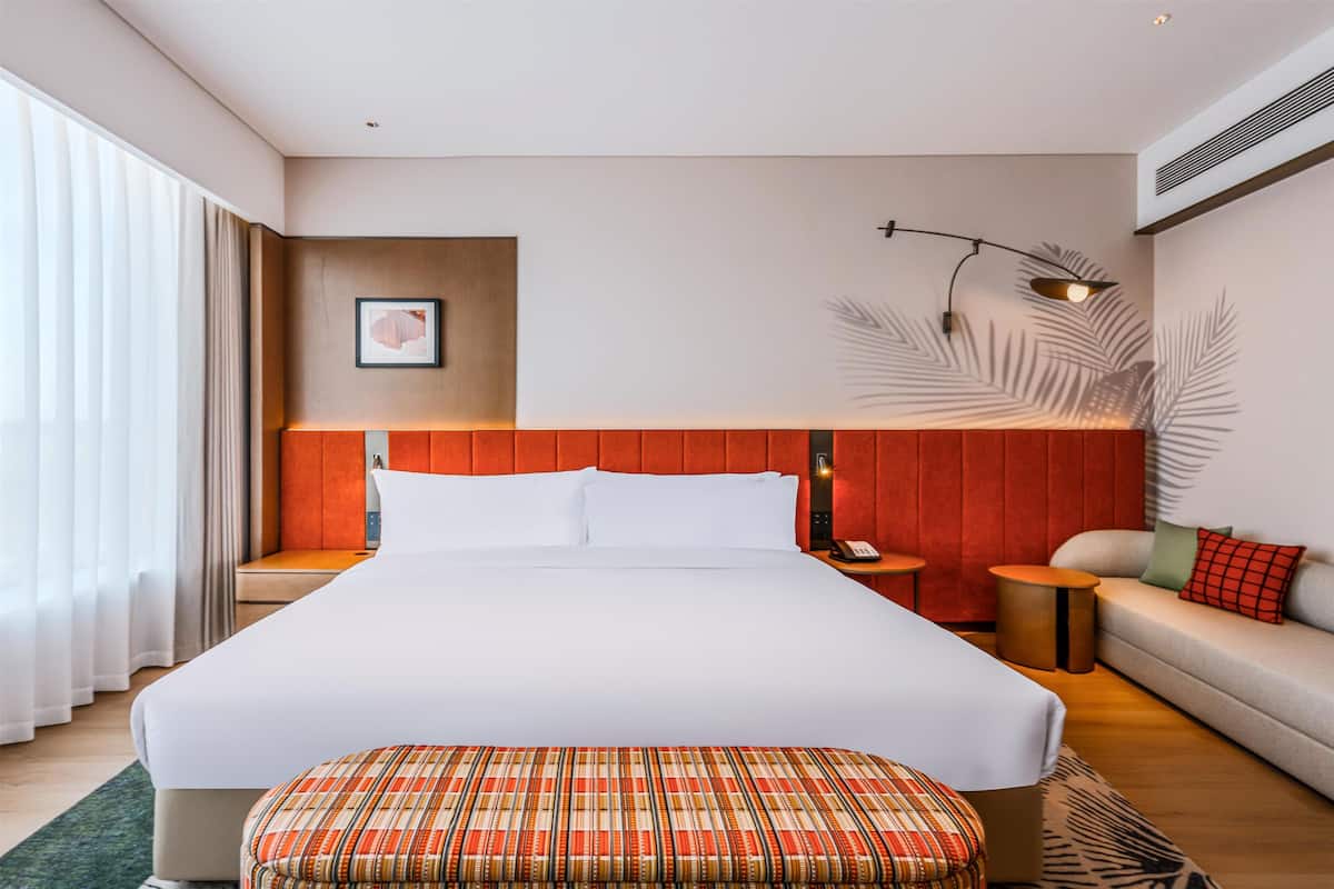 Een hotelkamer met een groot bed, een bank, een kleine tafel en een nachtkastje.