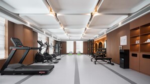 Une salle de sport moderne équipée de tapis de course, de vélos elliptiques et de matériel de musculation.