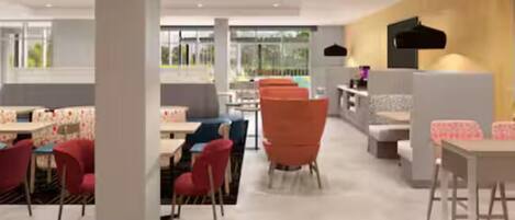 A modern interior with a mix of red and white furniture, a yellow accent wall, and large windows allowing natural light.