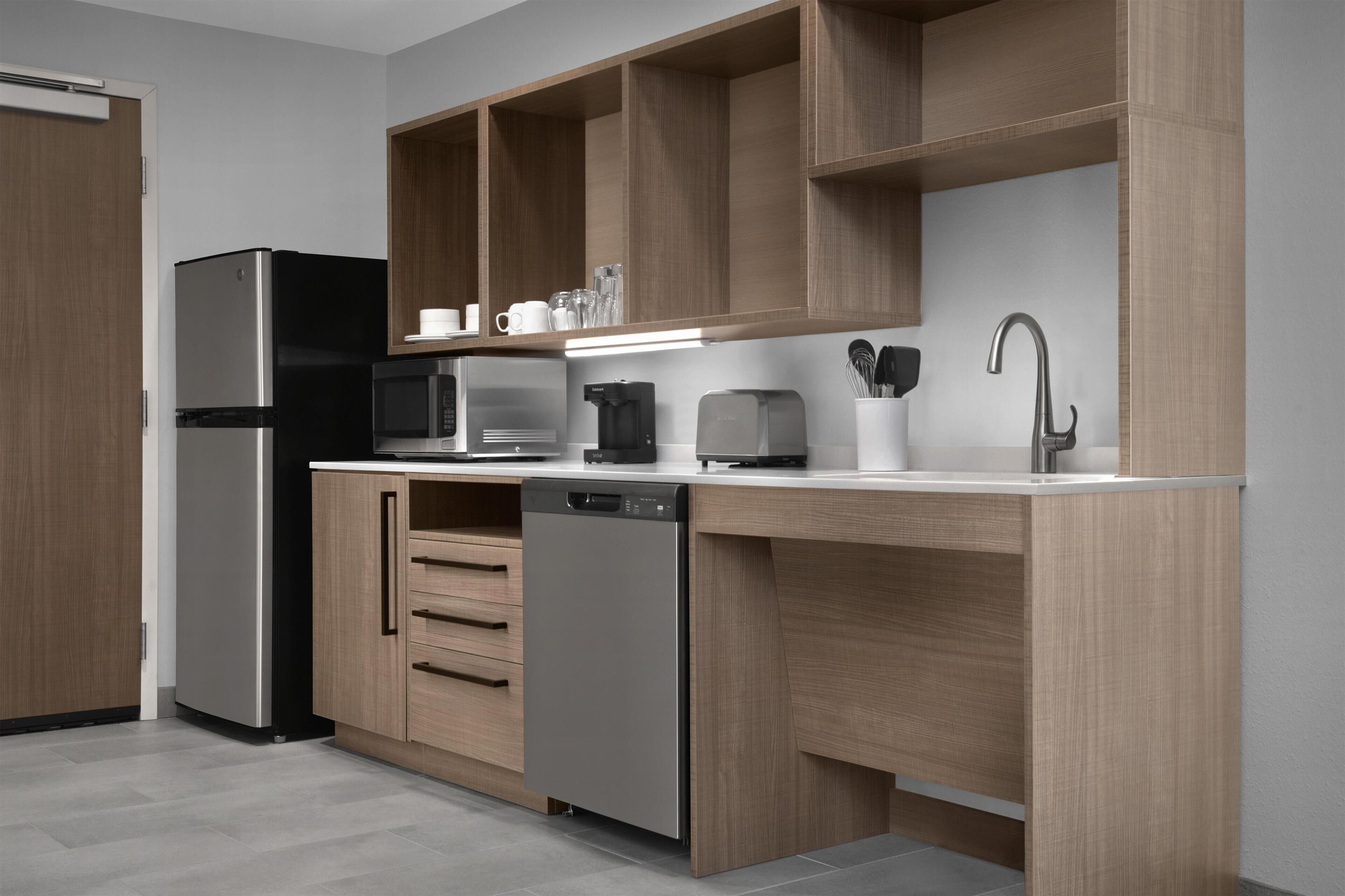 A modern kitchen with a refrigerator, microwave, toaster, and dishwasher.