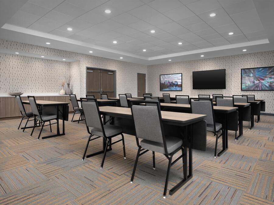 A conference room with multiple tables and chairs, a large screen, and a patterned carpet.