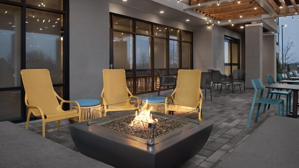 An outdoor seating area with a fire pit, wicker chairs, and tables. - Home2 Suites By Hilton Ashburn, Va (Ashburn)