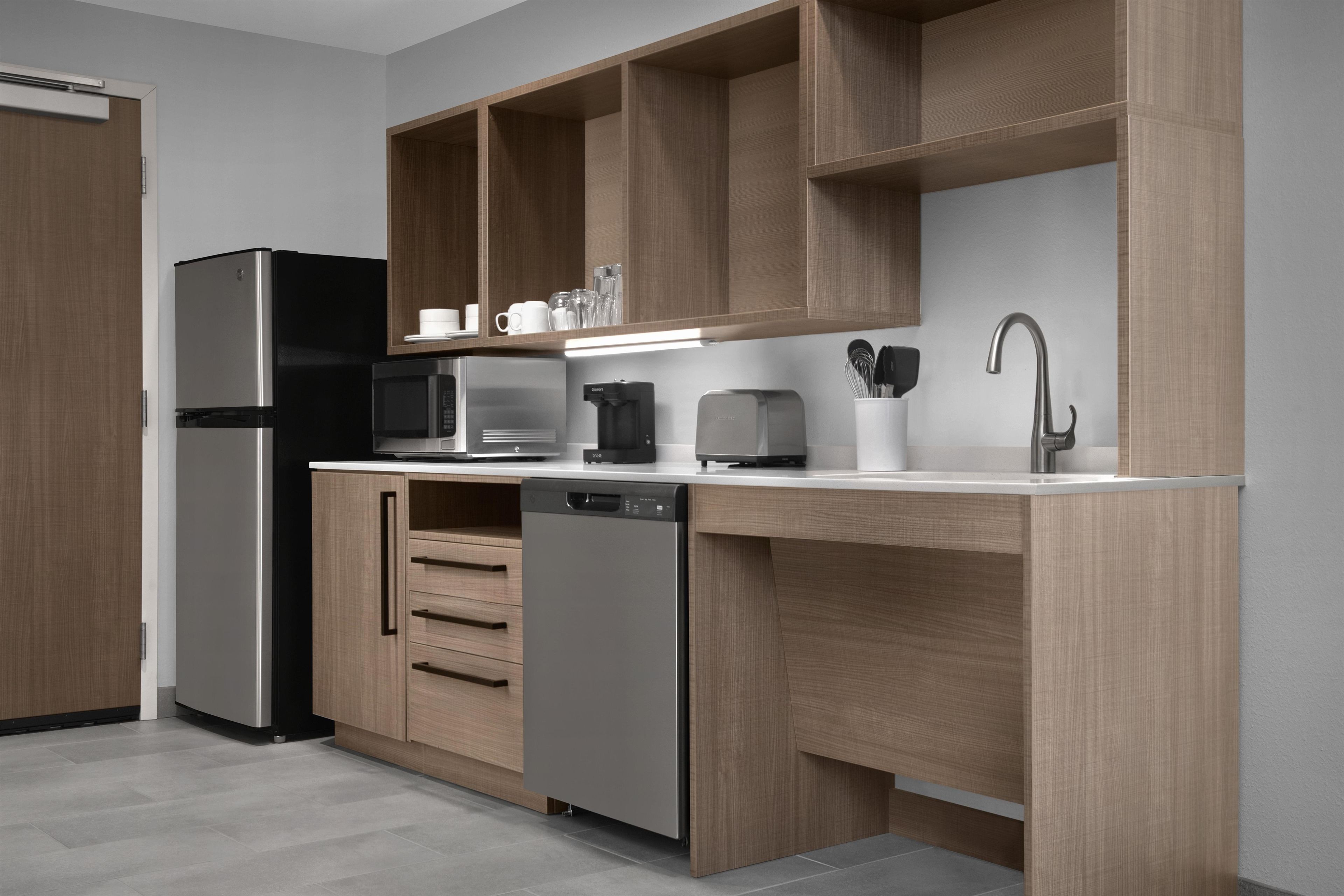 A modern kitchen with built-in appliances, wooden cabinetry, and a stainless steel sink.