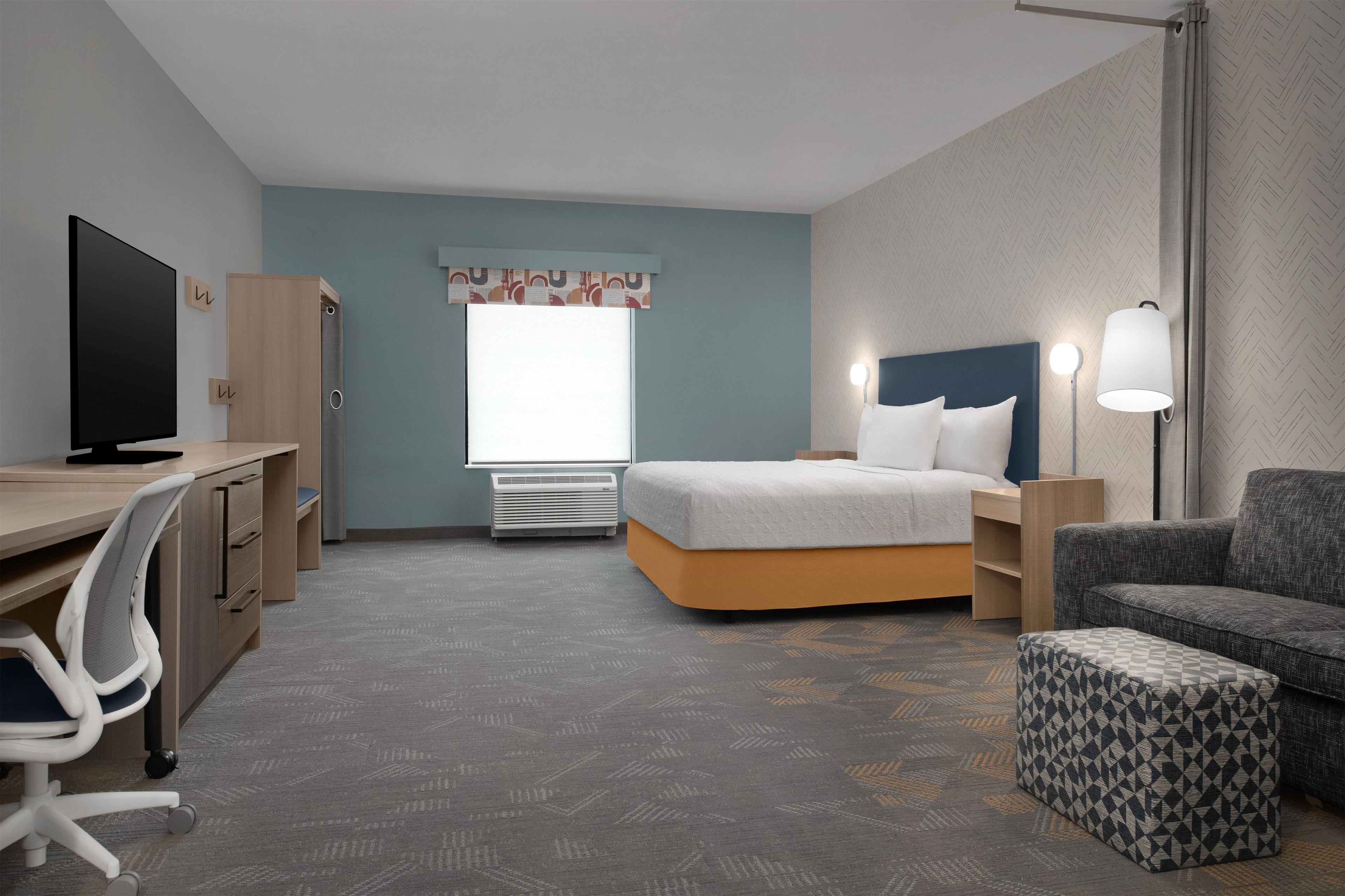 Une chambre d’hôtel équipée d’un lit, d’un bureau, d’une chaise et d’un téléviseur.
