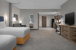 Una habitación de hotel con una cama, un escritorio, un televisor y una kitchenette.