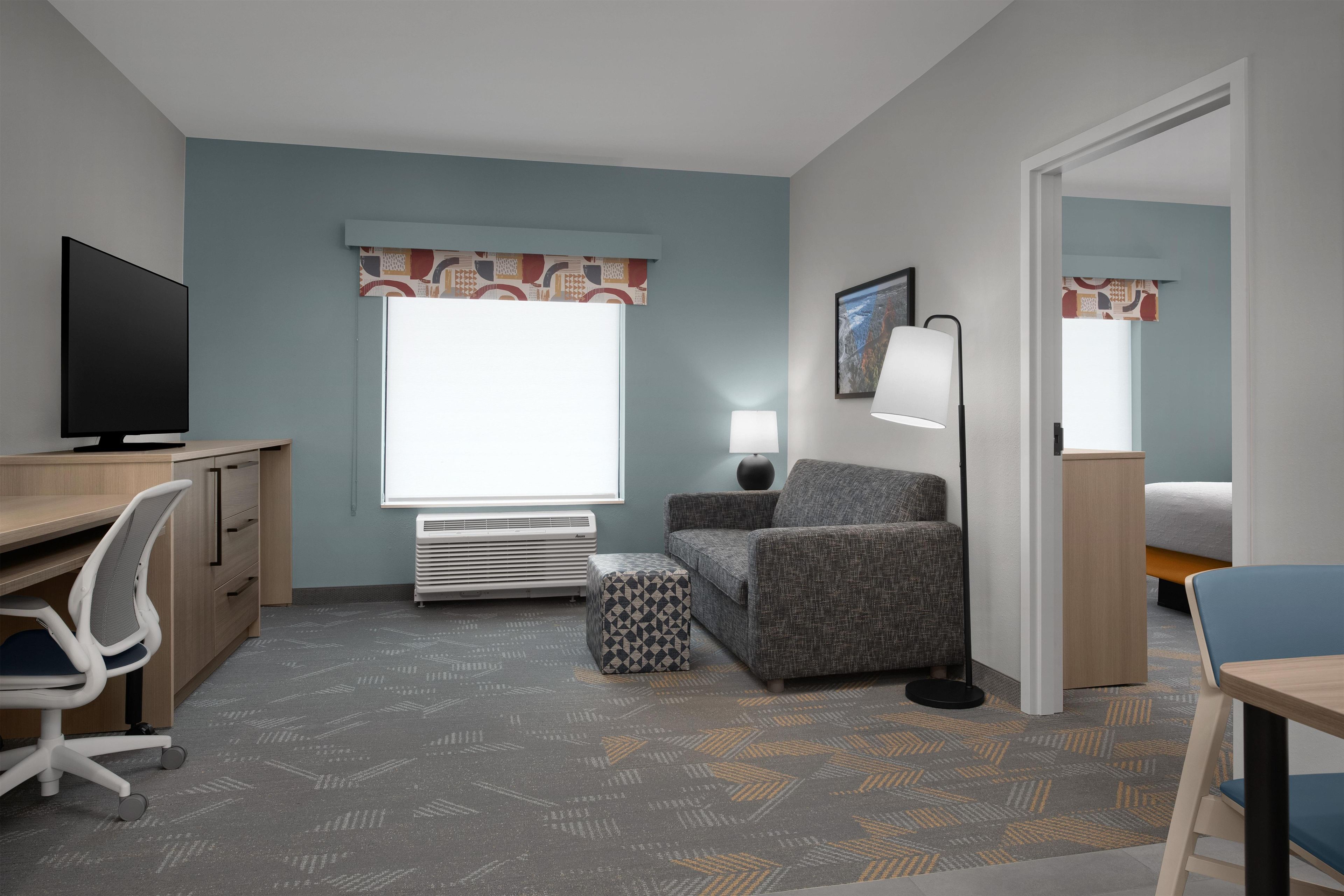 A hotel room with a desk, chair, sofa, and a bed.