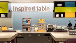 A breakfast area with an 'inspired table' sign, a 'good morning' sign, and various breakfast items and appliances. - Home2 Suites By Hilton Ashburn, Va (Ashburn)