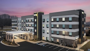 A multi-story hotel with a modern design, featuring a covered entrance and a parking lot. - Home2 Suites By Hilton Ashburn, Va (Ashburn)