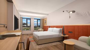 A modern hotel room with a large bed, a desk, a sofa, and a view of the outdoors.