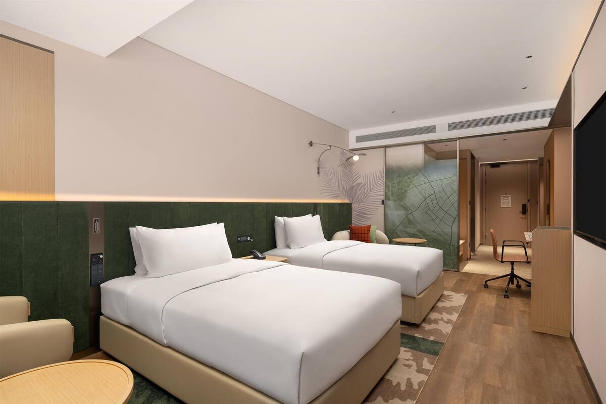 Een moderne hotelkamer met twee bedden, een bureau en een stoel.