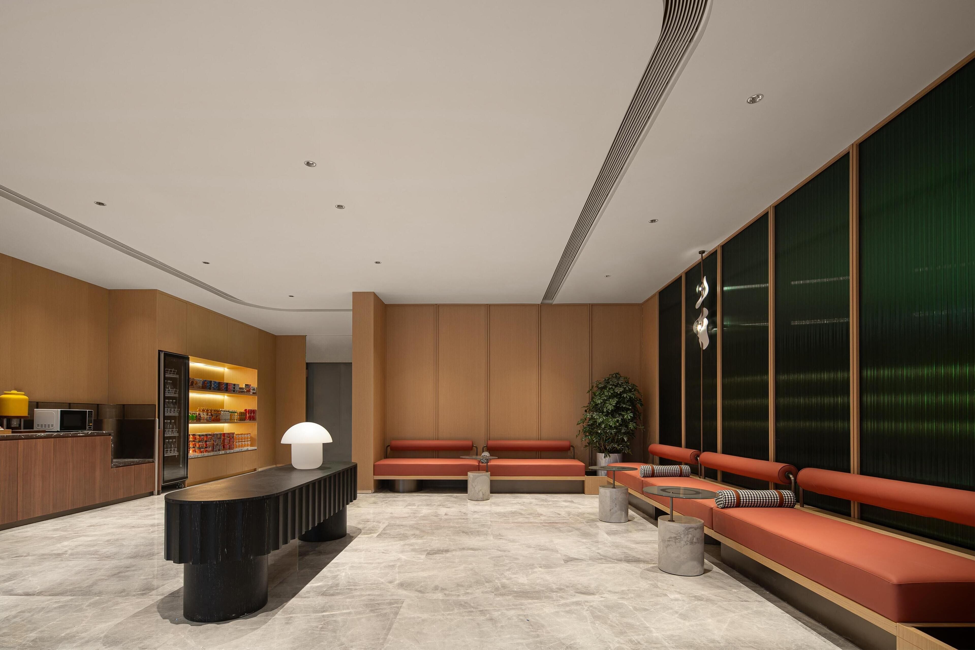 A modern lobby with a reception desk, seating area, and a large window with a view.