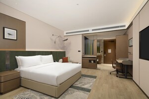 Una habitación de hotel moderna con una cama grande, un escritorio y un baño.