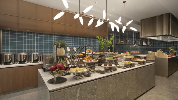 A buffet setup with various food items and a modern kitchen in the background. - Hilton Garden Inn Zhongwei Shapotou (Zhongwei)