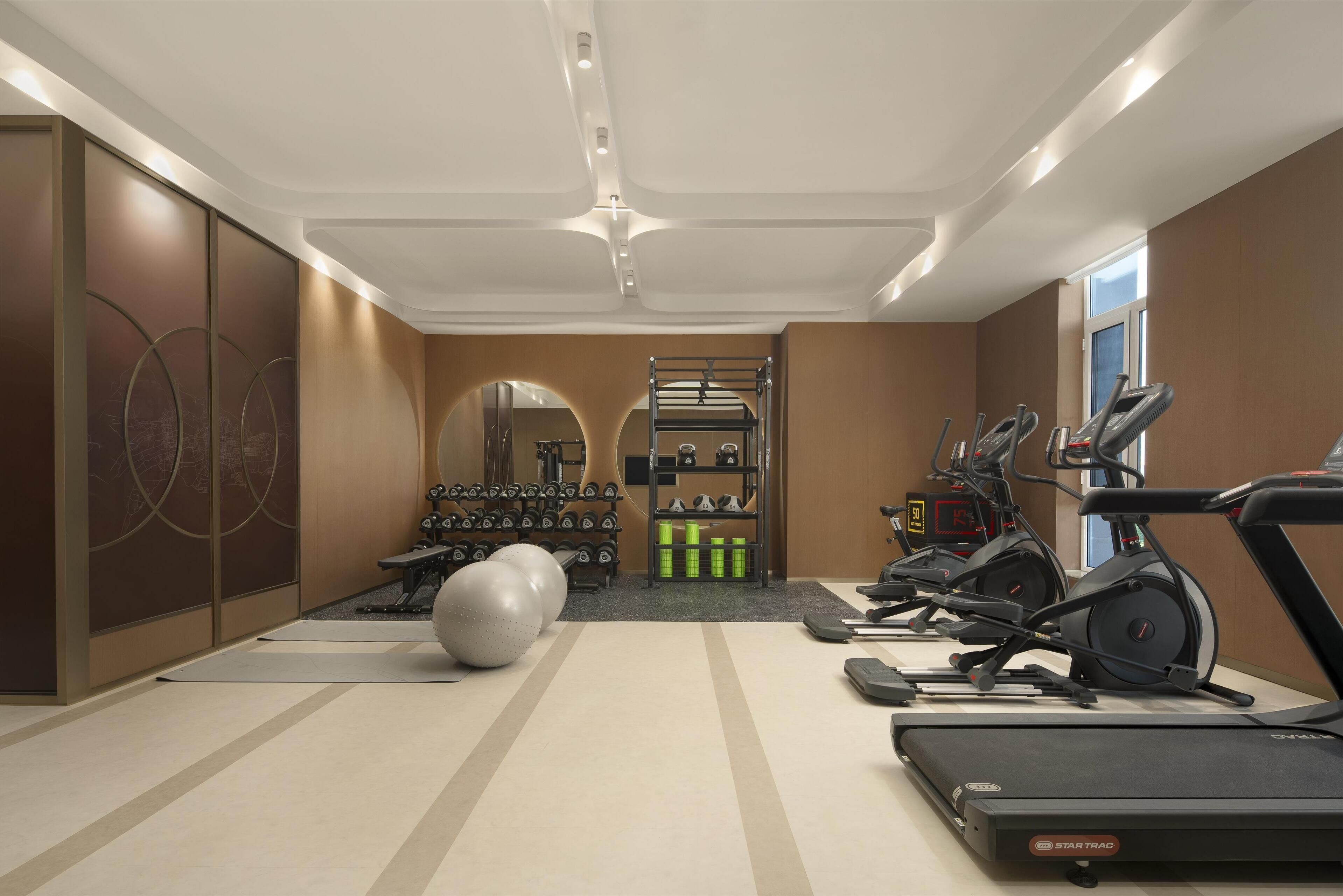 Un gimnasio con cintas de correr, elípticas y pesas libres.