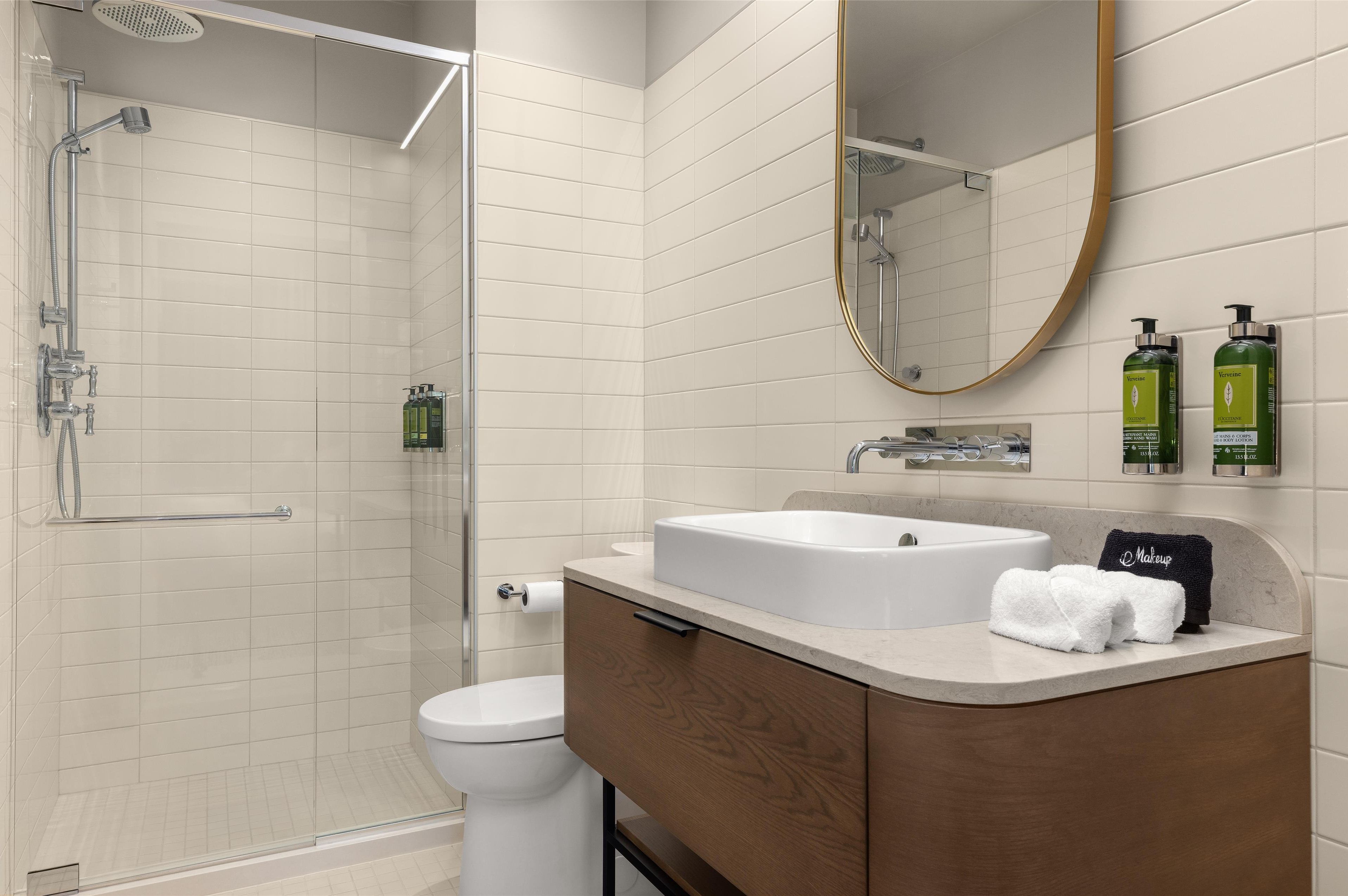 Een moderne badkamer met douche, toilet, wastafel en een grote spiegel.
