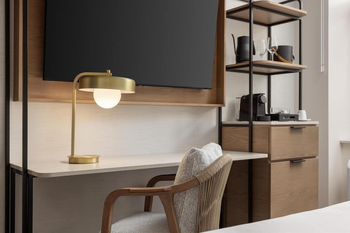 Et moderne arbejdsområde med et skrivebord, stol og et ophængt fjernsyn.