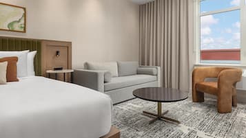 A hotel room with a bed, a sofa, a small table, and a chair.