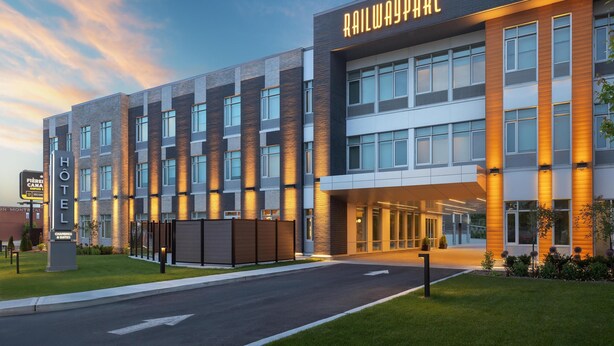 A modern hotel with a prominent "RAILWAYPARC" sign, a well-lit entrance, and a clean, landscaped exterior. - Hotel Railwayparc Montreal, Tapestry Collection By Hilton (Montreal)