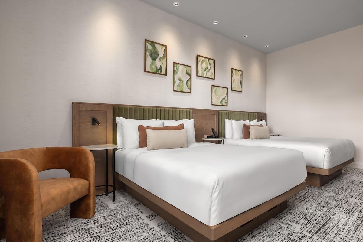 Et moderne hotelværelse med en stor seng, to sengeborde, en stol og et billede på væggen.