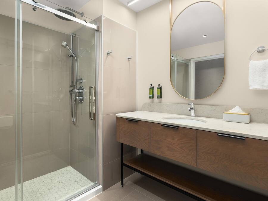 A modern bathroom with a glass-enclosed shower, a vanity with a sink, and a mirror.