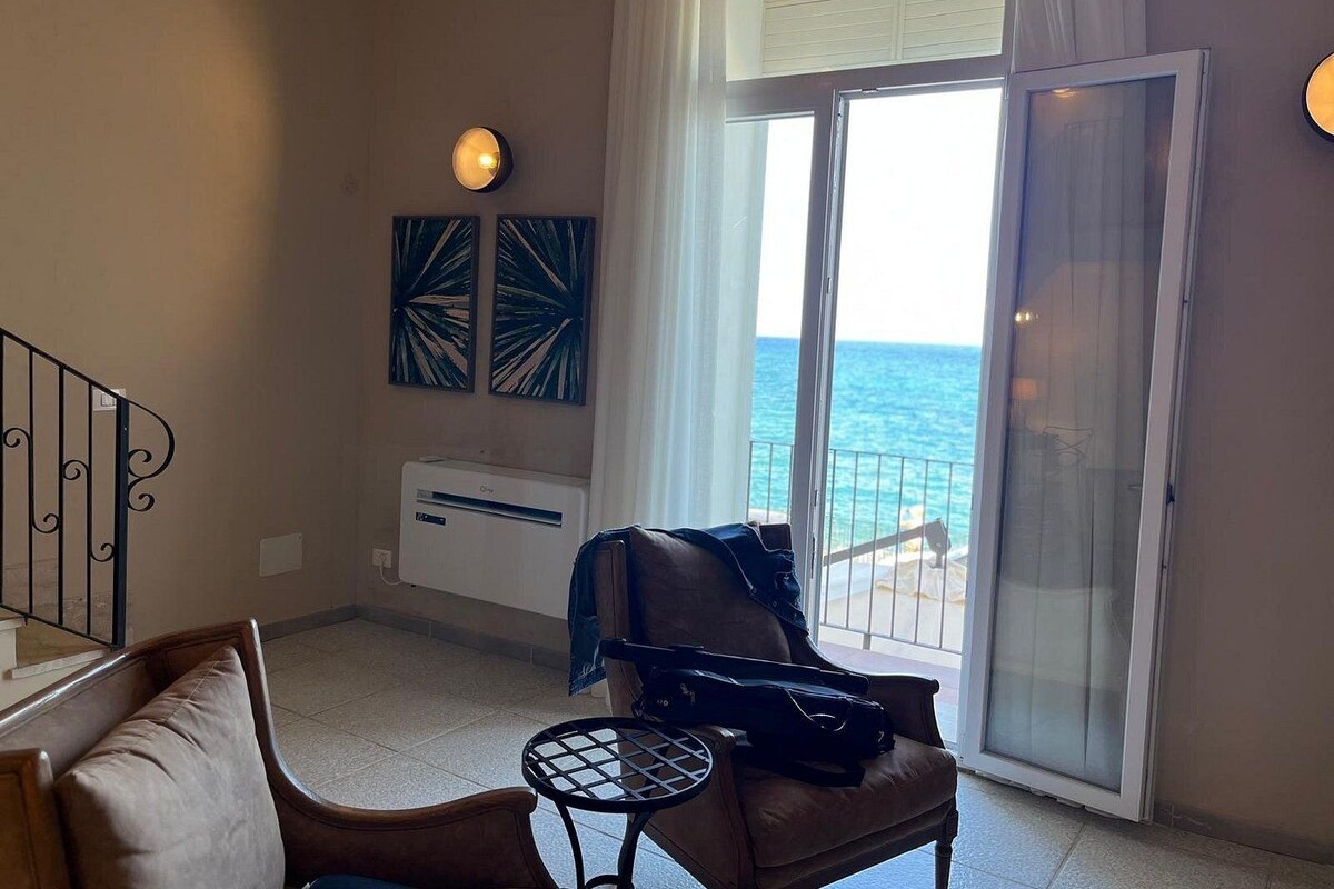 Une pièce avec un balcon, un canapé, une table et des œuvres d’art au mur.
