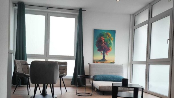 A modern living room with a sofa, a chair, a coffee table, and a painting on the wall. - Exclusive City Apartment Perfect Business Stays (Tuttlingen)