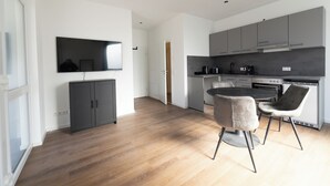 A modern kitchen with grey cabinets, a round dining table, and two chairs. - Exclusive City Apartment Perfect Business Stays (Tuttlingen)