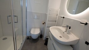 A modern bathroom with a glass shower enclosure, a white toilet, and a sink with a mirror above it. - Exclusive City Apartment Perfect Business Stays (Tuttlingen)