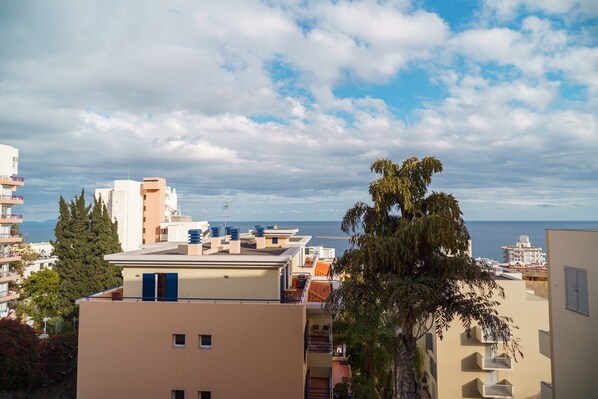 A coastal cityscape with modern buildings, a clear sky, and a view of the sea.