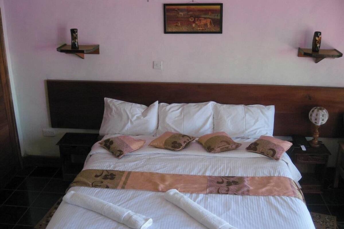 Una habitación de hotel con cama, almohadas, una colcha y un cuadro en la pared.