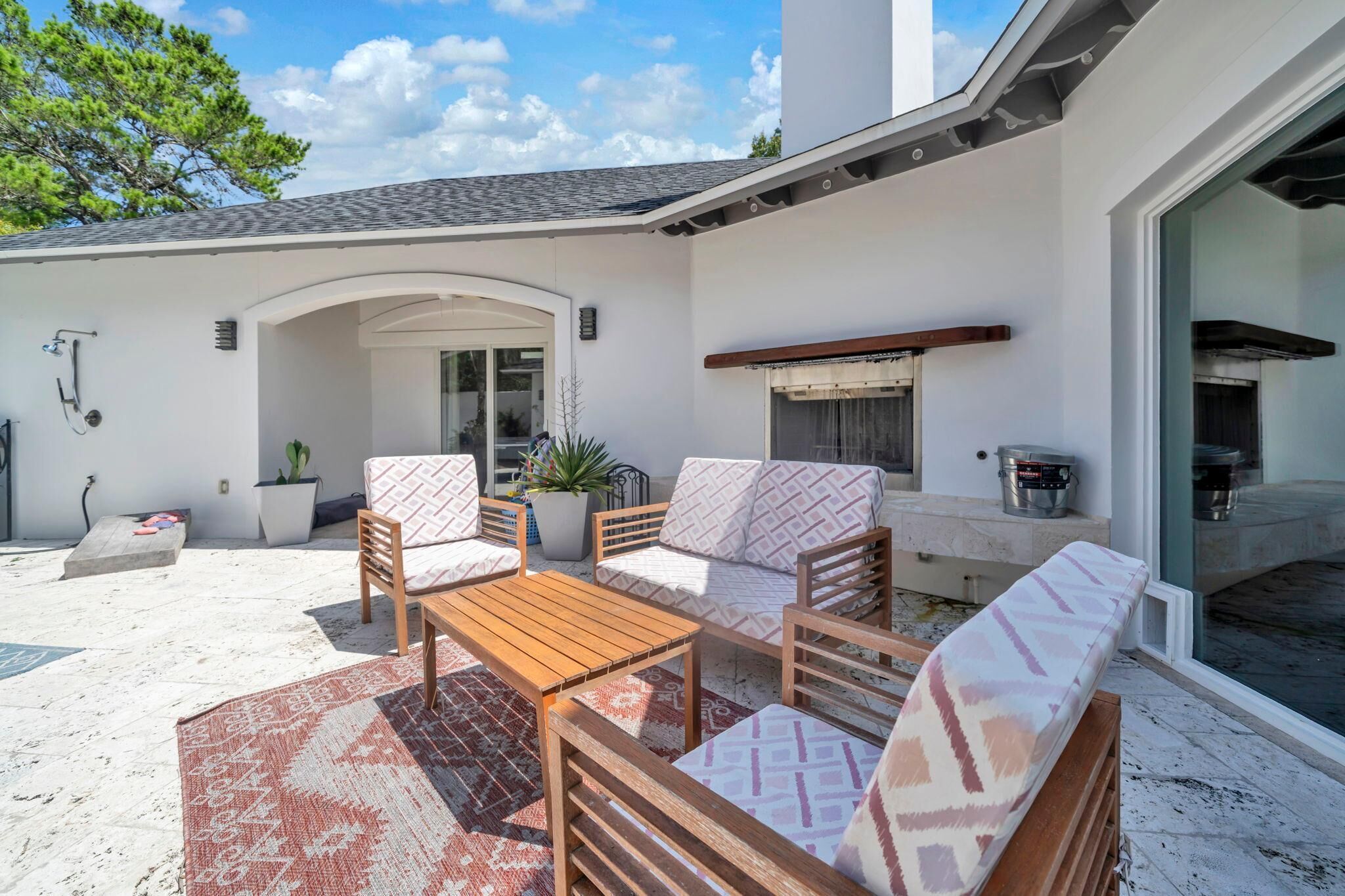 An outdoor patio area with a wooden table and chairs, a cushioned sofa, and a built-in grill.