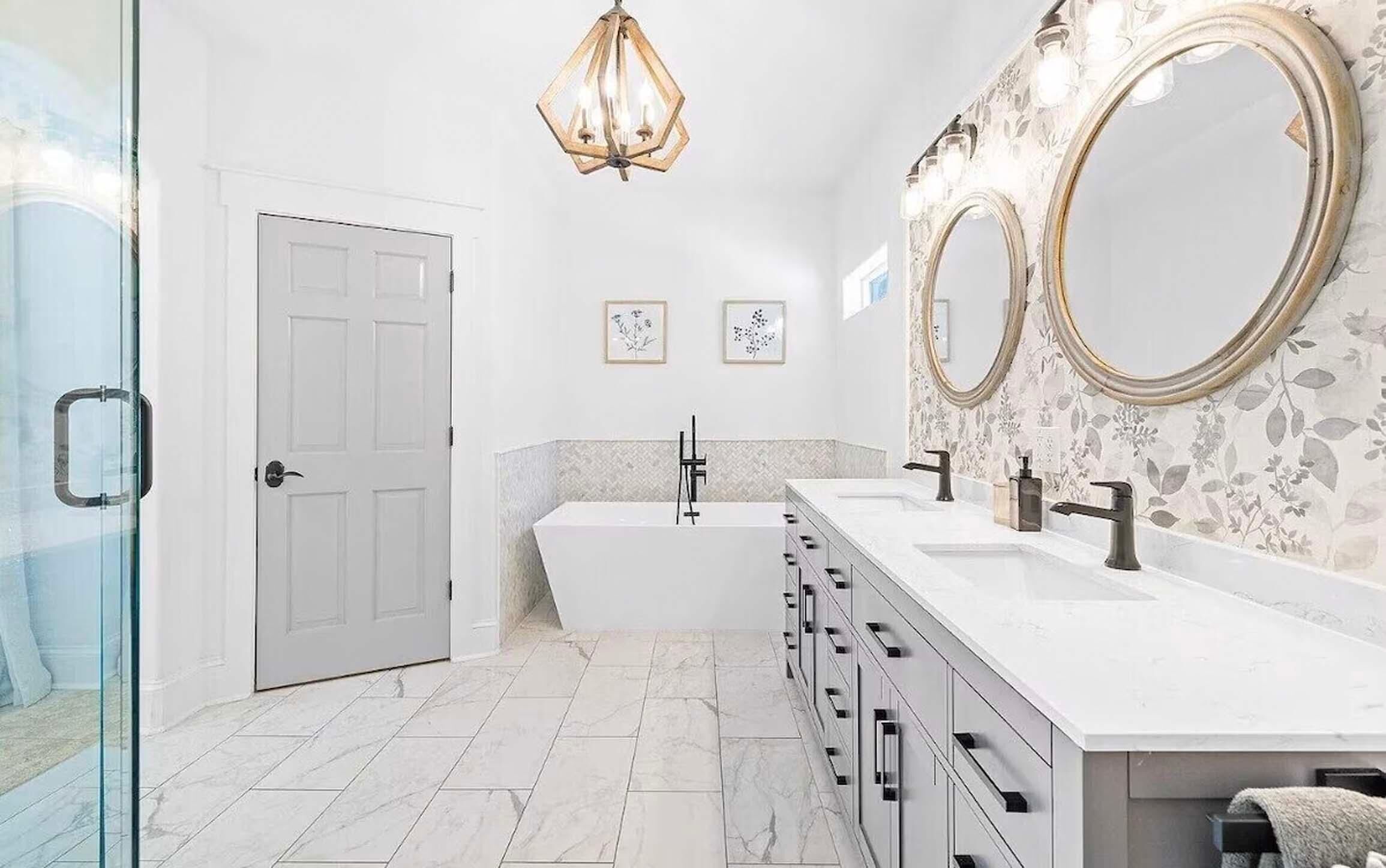 A modern bathroom with a double sink vanity, a freestanding bathtub, and two large mirrors.