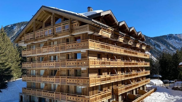 Eine mehrstöckige Holzhütte mit Balkonen in einer verschneiten Berglandschaft.