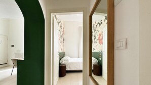 A hotel room with a bed, bedside table, and a large mirror. - Charme & design three-room (Bologna)