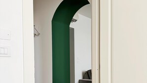 A hallway with a green archway leading to a room with a grey sofa. - Charme & design three-room (Bologna)