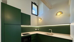 A compact kitchen with green cabinets, a white countertop, a built-in oven, and under-cabinet lighting. - Charme & design three-room (Bologna)
