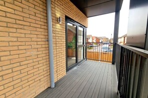 Enjoy the balcony with a wooden deck and metal railing, offering a convenient access to the interior space.