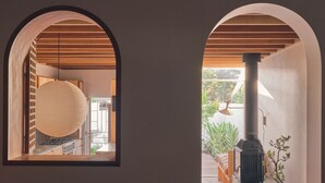 A view through an arched window into a kitchen area with a stove and a hanging paper lantern.
